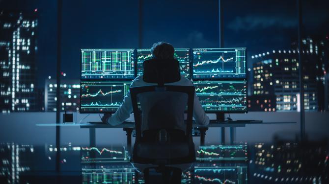 A cryptocurrency trader sitting at his desk”