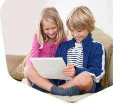 Two young children together looking on their tablet